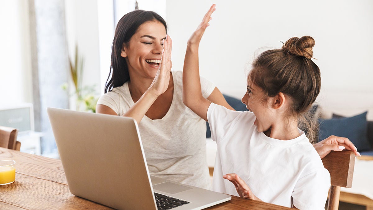 Happy mother and daughter high-fiving at computer