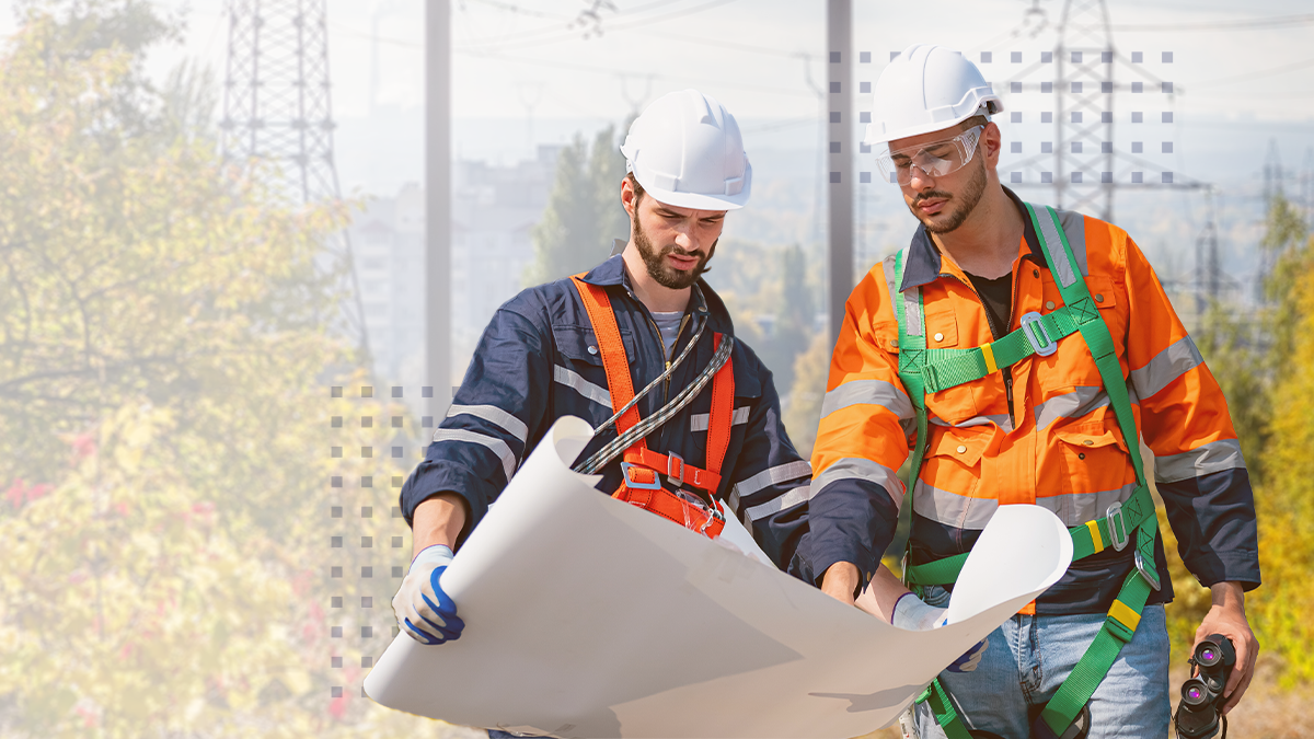 Team of electrical engineers analyzing blueprints during power project audit with blurred pylon in the background on the field 