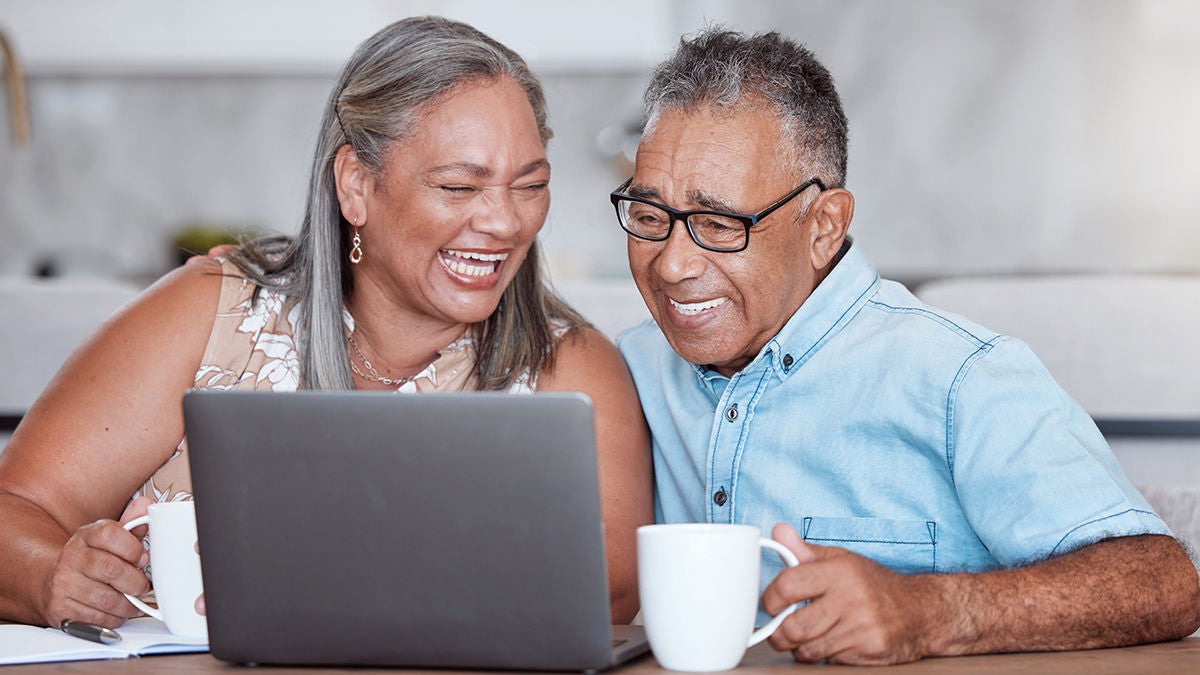 senior couple enjoying coffee with laptop