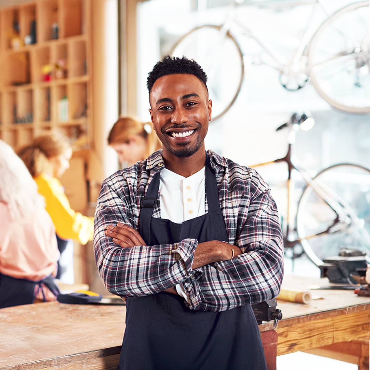 Small business bike shop business owner smiling with employees in background Small business bike shop business owner smiling with employees in background