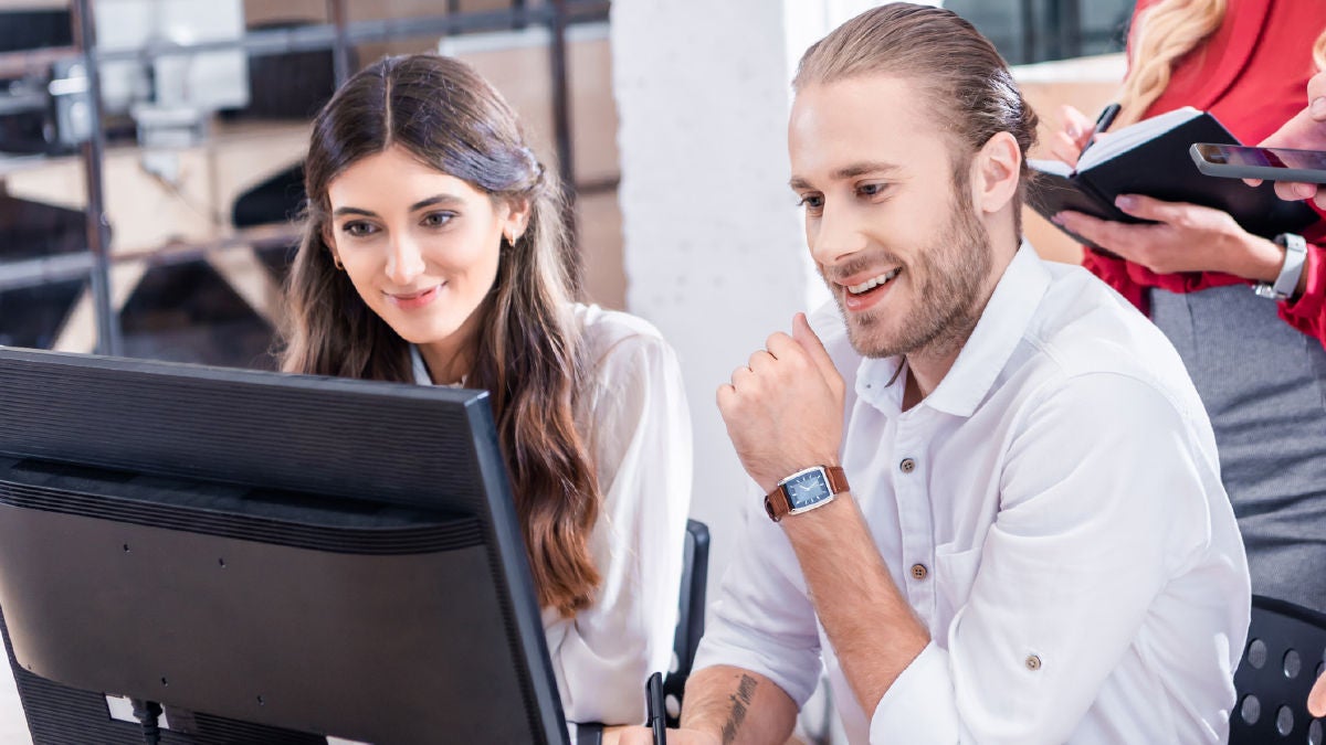 Smiling coworkers using a computer