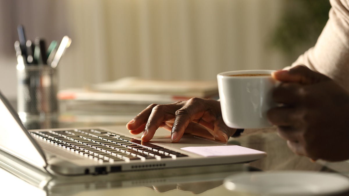 Worker on laptop and holding coffee cup